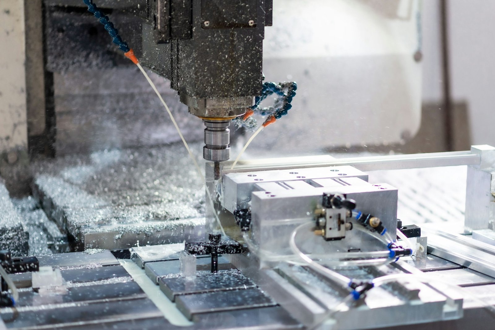 CNC machining centre milling a steel part with coolant